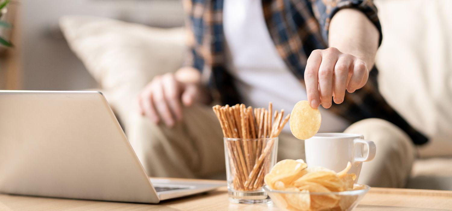 man taking a snack in front of computer