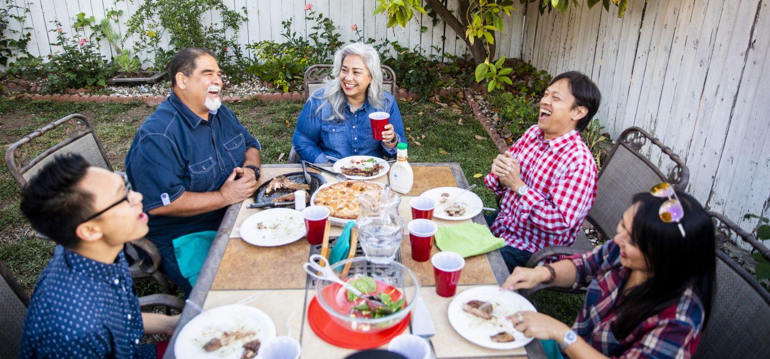 group of people eat in the backyard laughing